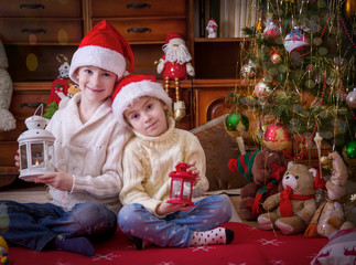 wo children with lanterns under Christmas tree