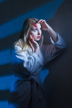 Concept: victim, accident, domestic violence. Beautiful young woman in bathrobe suffer head trauma in dramatic light.
