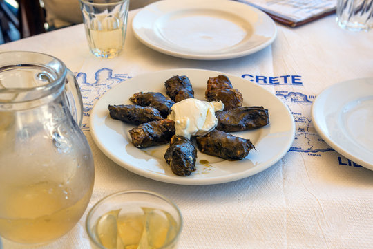 Traditional greek food made from grape leaf filled with rice served with tzaziki sauce in restaurant on Crete Island. Greece.