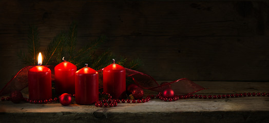 Four red candles, one of them burning on the first advent, christmas decoration, panorama banner or...