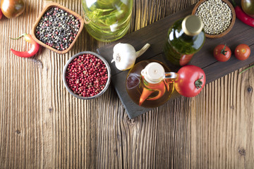 Olive oil and rosemary, chili pepper, many different tomatoes, garlic, red, white, green pepper on old wooden table. Extra virgin olive oil cruets and flavored olive oils with rosemary and chili.