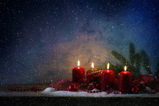 Four red advent candles burning in the snow against a blue vintage background, generous copy space