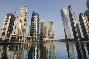 Obraz na płótnie Canvas Architecture theme. Panoramic view with modern skyscrapers and water pier of Dubai Marina at sunrise,, United Arab Emirates. Luxurious property.