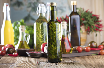 Olive oil and rosemary, chili pepper, many different tomatoes, garlic, red, white, green pepper on old wooden table. Extra virgin olive oil cruets and flavored olive oils with rosemary and chili.