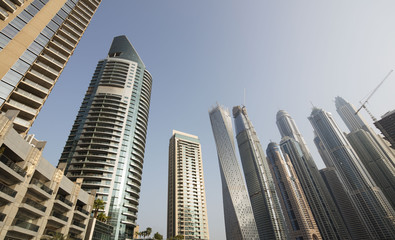 Fototapeta premium Architecture theme. Panoramic view with modern skyscrapers and water pier of Dubai Marina at sunrise,, United Arab Emirates. Luxurious property.