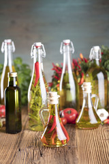 Olive oil and rosemary, chili pepper, many different tomatoes, garlic, red, white, green pepper on old wooden table. Extra virgin olive oil cruets and flavored olive oils with rosemary and chili.