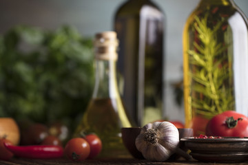 Olive oil and rosemary, chili pepper, many different tomatoes, garlic, red, white, green pepper on old wooden table. Extra virgin olive oil cruets and flavored olive oils with rosemary and chili.