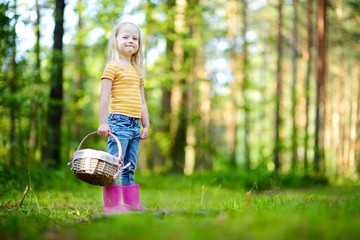 Adorable little girl picking foxberries in the forest