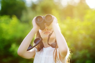 Funny little girl looking through binoculars
