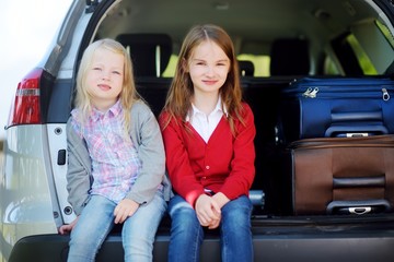 Two adorable little sitting in a car before going on vacations with their parents