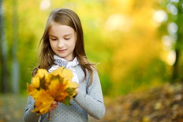 Cute little girl having fun on beautiful autumn day