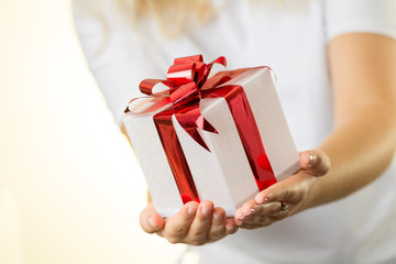 blonde girl woman holds white Christmas gift present with shiny red ribbon nice hands white background