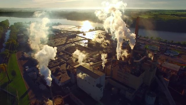 factory smokestacks, steaming and smoking, stunningly back-lit by the sunrise, stunning aerial view.