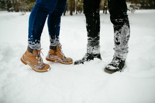Legs Man and woman in winter boots standing in the snow next to each other.