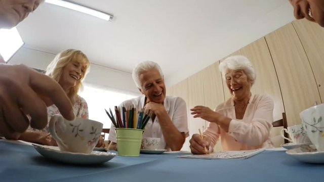 Senior man and woman painting while having coffee