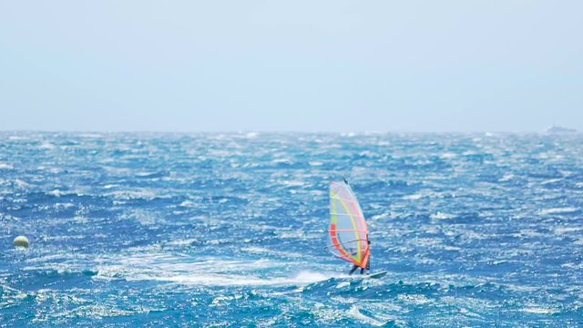 Athletic man windsurfing in the ocean, active lifestyle, popular extreme sport