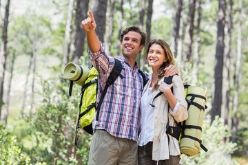 Happy man pointing while standing with partner in forest 