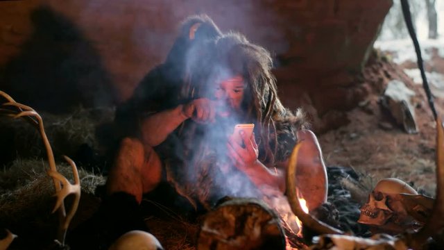 Prehistoric caveman using smartphone