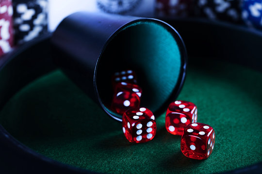 Casino theme. High contrast image of casino roulette, poker game, dice game, poker chips on a gaming table, all on colorful bokeh background. Place for typography and logo.