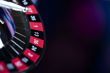 Casino theme. High contrast image of casino roulette, poker game, dice game, poker chips on a gaming table, all on colorful bokeh background. Place for typography and logo.