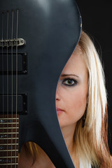 Blonde woman holding electric guitar, black background