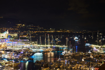 World Fair MYS Monaco Yacht Show at night, Port Hercules, luxury megayachts, many shuttles, party time, boat traffic, long exposure, aerial view, cityscape, night lights, illumination of boat