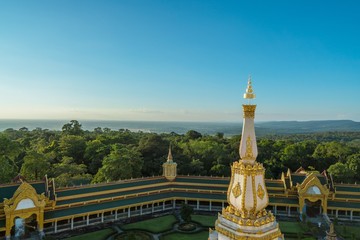 Fototapeta na wymiar Temple scene : beautiful White and gold pagoda with daylight blue sky. High of pagoda in the mountain at Maha Chedi Mongkhol temple, Roi Et, Thailand.