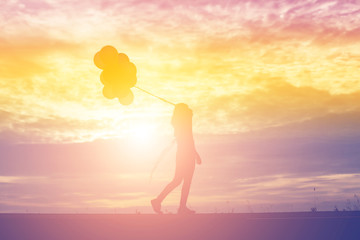 silhouette of young woman holding colorful of balloons with suns