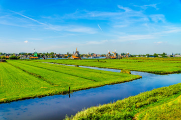 Typical Dutch Landscape with open Fields, Canals and Dutch Windmill at the Historic Village of Zaanse Schans in the Netherlands