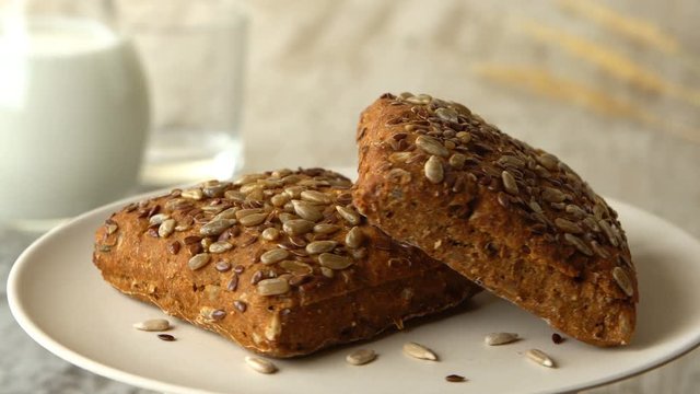 Two delicious homemade small loafs of bread with seeds. Milk-jug, on wooden rustic table. Looped.