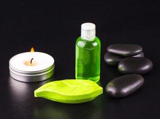 Obraz na płótnie Canvas Soap, candle, bottle of oil and spa stones on black table.