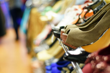 Rows of stylish women's shoes and high heels on a rack for sale at a clothing store
