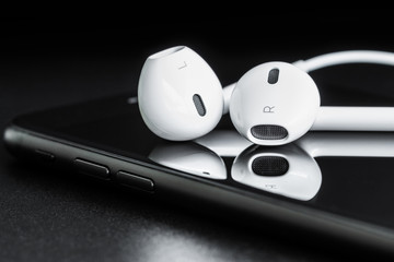 Close-up headphone stack on phone, modern phone's earbuds device
