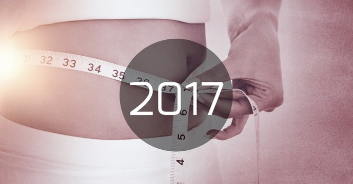 Woman measuring her waist against 2017
