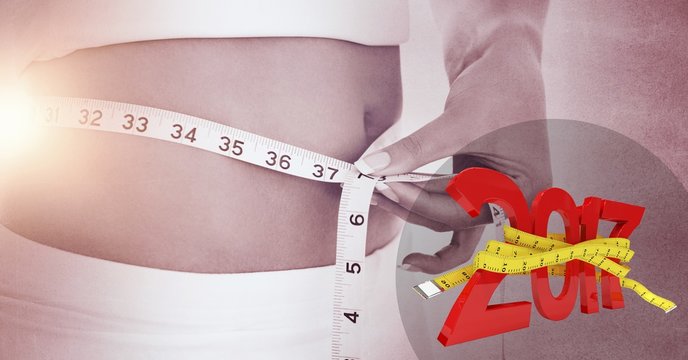 Woman measuring her waist against 2017