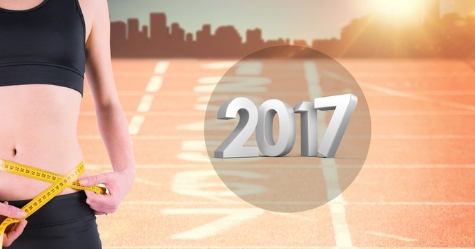 Mid section of woman measuring her waist against 2017