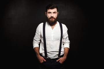 Young handsome man posing over black background.