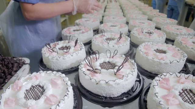 Pastry Chef Decorate Cakes with chocolate, cream and sugar on a cake production factory. 4K.
