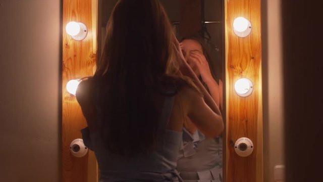 Young attractive Caucasian female checking her make up in dressing room mirror.  60 FPS slow motion shot, 4K UHD