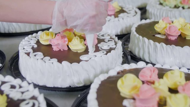 Pastry Chef Decorate Cakes with chocolate, cream and sugar on a cake production factory. 4K.