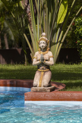 Traditional Thai sculpture and swimming pool in tropical garden. Thailand