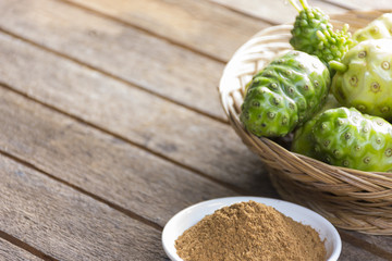 Fototapeta premium Noni fruit and noni powder on wooden table.Fruit for health and herb for health