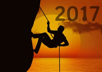 Fototapeta na wymiar Composite image of 2017 with silhouette of man climbing a cliff 