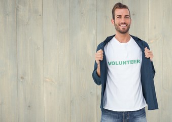 Smiling male volunteer standing against wooden background