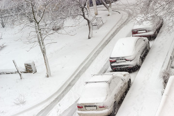 Three parked one after another cars during snowfall