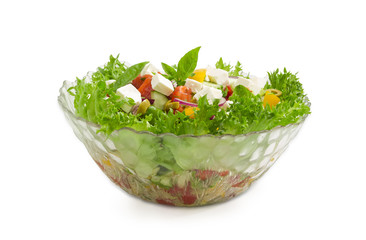 Greek salad in glass salad bowl on a light background