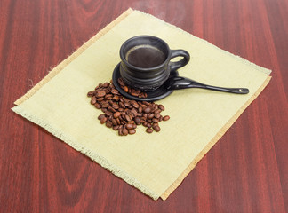 Coffee beans and freshly brewed coffee in black ceramic cup