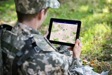 Soldier using map on tablet for orientation at forest