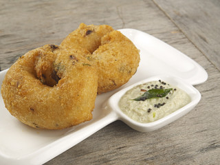 methu vadai with coconut chutney served in a dip plate on wooden
