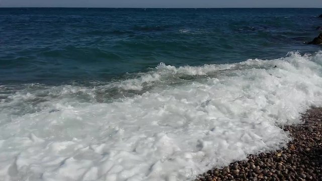 Sea waves surf on pebble coast of Black Sea
